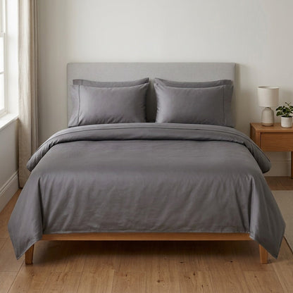 Grey brushed microfibre sheet set on a made bed, showing the fitted sheet, turned-back flat sheet and two pillowcases